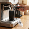 A drink bottle with a sleek black design and a branding logo, positioned under an espresso machine.