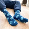 A pair of blue crew socks featuring smiling face patterns, with one sock slightly offset from the other.
