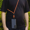 A phone lanyard with an orange cord is worn around the neck, holding a black smartphone.