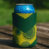 A green and yellow neoprene stubby holder with a patterned design, holding a blue drink can.