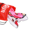 A red polyester drawstring bag with a zippered pocket, filled with a vibrant pink towel featuring a playful design.