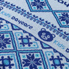 A close-up of a patterned fabric in shades of blue featuring geometric designs and a bear logo.