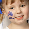 A child with a temporary tattoo of Australia featuring a small flag on their cheek, smiling cheerfully.