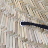 A close-up of a straw hat showcasing the woven texture and a black string threaded through a metal grommet.