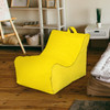 A yellow bean bag chair in a living space with wooden flooring and light furniture. It features a carrying handle.