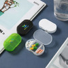 Three pill boxes in green, black, and white, displaying various pills inside a transparent compartment.