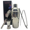 A drink bottle with a shiny silver cocktail shaker, strainer, jigger, tongs, and packaging in the background.