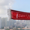 A red scarf with white fringe and a logo, featuring a suction cap on one end.
