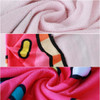 A custom-shaped beach towel featuring a pink background with vibrant patterns in red, yellow, and blue, showcasing its soft texture.