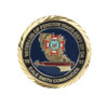 A commemorative gold coin pin featuring a detailed emblem, with blue, gold, and red colours, surrounded by a decorative border.