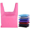 A pink reusable foldaway shopping bag sits alongside folded bags in various colours, including blue, purple, and black.