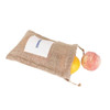 A jute net produce bag in natural brown contains an orange and a peach, with a logo visible on the front.