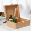A wooden case with a natural finish, containing a brown glass bottle and a green glass bottle with reeds.