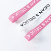 Ribbed fabric ribbon in pink and white, featuring a logo, suitable for various decorative uses.