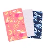 Three sheets of wrapping paper featuring vibrant patterns: pink with geometric shapes, white with subtle design, and navy blue with wave motifs.