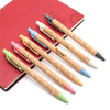 A collection of eco cork pens in various colours, displayed alongside a red notebook with a clock design.