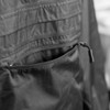 A close-up of a black windbreaker jacket featuring a zippered pocket and textured fabric.