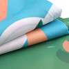 A folded outdoor blanket featuring a vibrant design with blue, green, and peach colours, along with a logo.