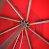 A red patio umbrella with a sturdy metal frame, viewed from underneath, showcasing its structure.