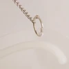 A clear, flexible sign holder with a silver metal hook attached to a chain.