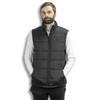A man in a dark grey puffer vest stands with hands in pockets against a white background, featuring a logo on the vest.