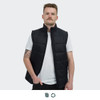 A man wearing a black puffer vest over a white t-shirt, standing against a plain background. The vest features a logo.