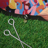 Oval-shaped pop-up banner featuring vibrant graphics, set on green grass with metal pegs beside it.