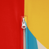 A close-up of a vibrant fabric featuring red, yellow, and blue sections with a zipper detail.
