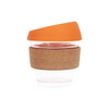 A reusable glass coffee cup with a cork band and an orange silicone lid.