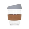 A reusable glass coffee cup with a cork band and grey lid, featuring a clear body for visible contents.
