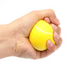 A yellow tennis-shaped stress reliever being squeezed in a hand, designed for fun and stress relief.