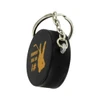 A black hockey puck stress reliever attached to a silver keyring, featuring a logo or branding.