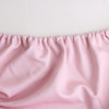 A pink rectangle table topper with gathered edge detailing, made from soft fabric. It features a logo.