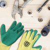Latex dipped gloves in green and yellow, placed on a wooden surface alongside various tools.