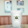 A frosted plastic stadium cup with a printed design of a T-shirt and heart, set in a blurred indoor background.