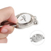 A metal golfers divot tool with a ball marker featuring a logo, held between fingers, showcasing shiny silver and white colours.