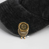 A 40mm custom antique golf ball marker in gold and bronze resting on a dark grey cap. Features a logo.