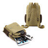A khaki canvas sling backpack with brown accents, featuring multiple pockets and a variety of items inside.