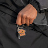 A wooden keyring shaped like a house, held by a hand, featuring a metal key and a logo.