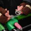 A round trolley coin keyring being removed, held by hands wearing brown knitted gloves. The trolley has a green handle.