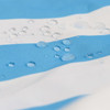 A close-up of a blue and white striped fabric with water droplets on its surface, featuring a logo.
