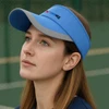 A blue sun visor with a grey brim, featuring a logo. The visor is worn by a woman looking upwards.