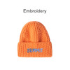 An orange twisted cable cuffed beanie with a single logo on the front.
