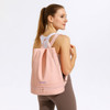A pink backpack with a handle and adjustable straps, featuring a logo on the front.