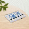 A4 wiro side bound notebook with a blue sea turtle design, featuring a black elastic band, resting on a wooden surface.