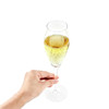 A hand holding a tall, clear tulip champagne glass filled with sparkling yellow liquid.