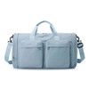 A foldable travel duffle bag in light blue with two front pockets and a detachable shoulder strap.