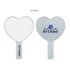 A heart-shaped handheld mirror with a clear handle, featuring a logo printed on one side.