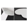 A heart-shaped handheld mirror with a white handle, featuring a smooth reflective surface.