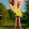 A drink bottle being opened with a yellow custom shape trolley coin keyring bottle opener, featuring a logo.